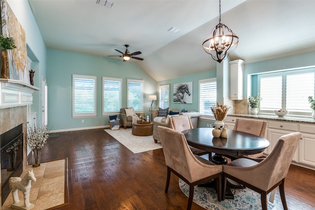 dining area with vaulted ceiling, dark hardwood / wood-style floors, ceiling fan with notable chandelier, and a fireplace