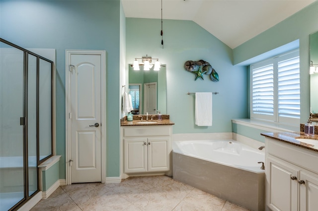 bathroom with a closet, a sink, vaulted ceiling, a shower stall, and two vanities