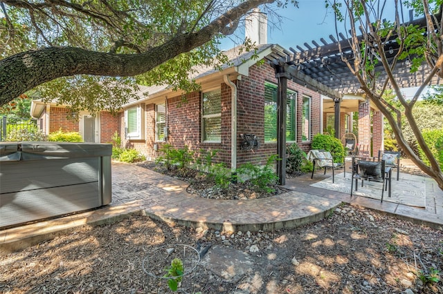 view of home's exterior featuring brick siding, a patio, a hot tub, and a pergola