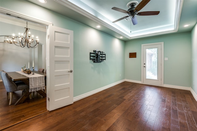 interior space with a raised ceiling, ceiling fan with notable chandelier, and hardwood / wood-style flooring