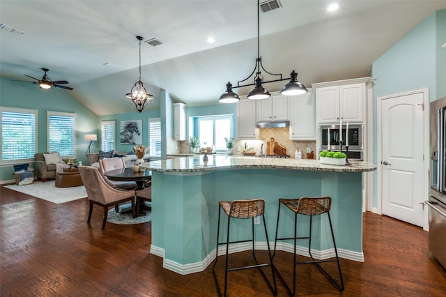 kitchen featuring light stone counters, pendant lighting, white cabinetry, and visible vents