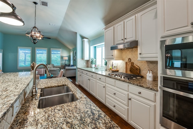 kitchen with tasteful backsplash, appliances with stainless steel finishes, hanging light fixtures, white cabinets, and sink