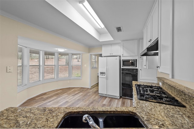 kitchen featuring light stone counters, black appliances, white cabinets, light hardwood / wood-style flooring, and ornamental molding