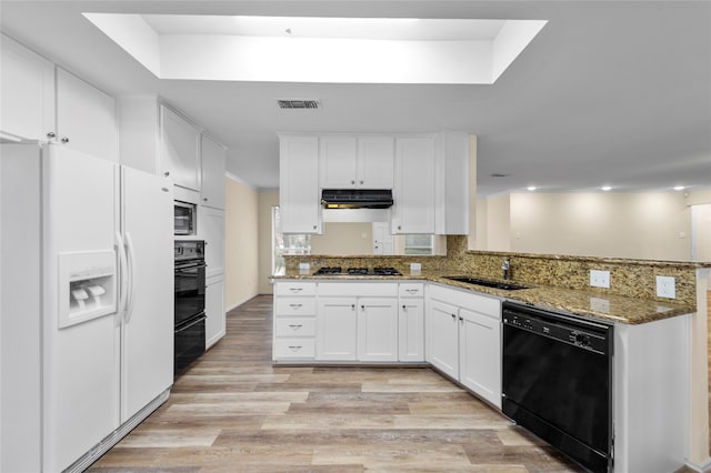 kitchen featuring black appliances, light hardwood / wood-style floors, kitchen peninsula, dark stone counters, and white cabinetry