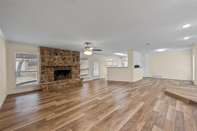 unfurnished living room featuring a fireplace, ceiling fan, light hardwood / wood-style flooring, and a healthy amount of sunlight