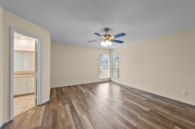 spare room with baseboards, ceiling fan, and wood finished floors