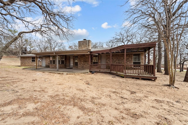 rear view of property with a chimney, a patio area, and brick siding