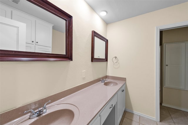 bathroom with double vanity, baseboards, a sink, and tile patterned flooring