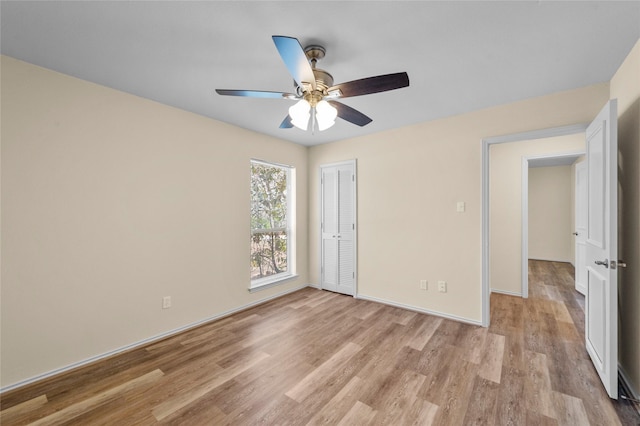 unfurnished bedroom featuring baseboards, a ceiling fan, a closet, and light wood-style flooring