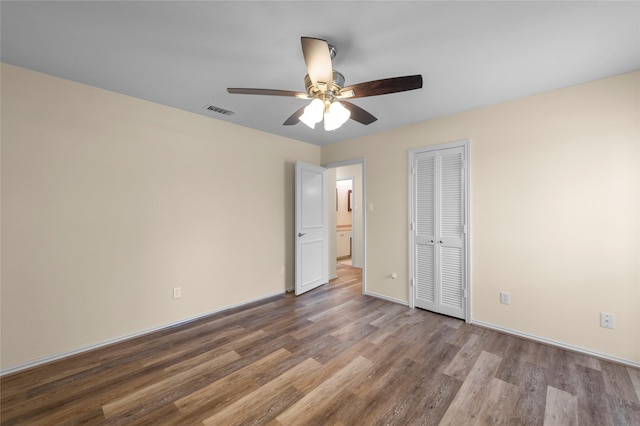 unfurnished bedroom with a closet, visible vents, wood finished floors, baseboards, and ceiling fan