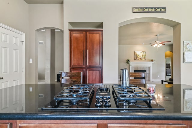 kitchen with ceiling fan, a tiled fireplace, and black gas cooktop