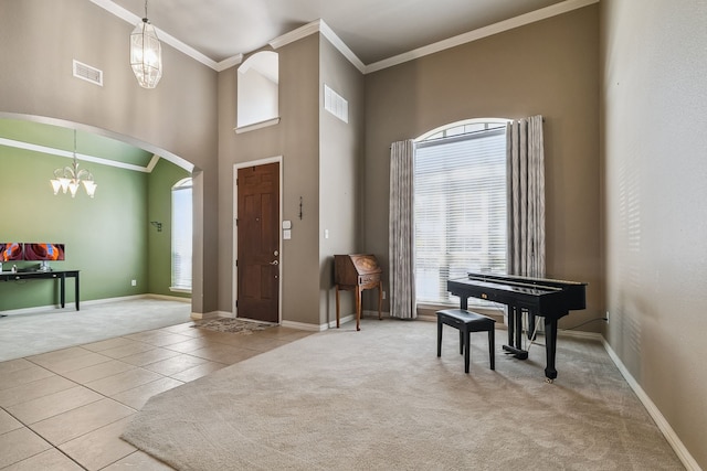 tiled entryway with a high ceiling, a chandelier, and crown molding