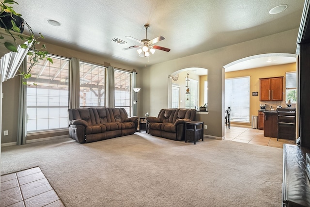 tiled living room with a textured ceiling and ceiling fan