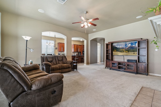 living room with ceiling fan with notable chandelier and light colored carpet