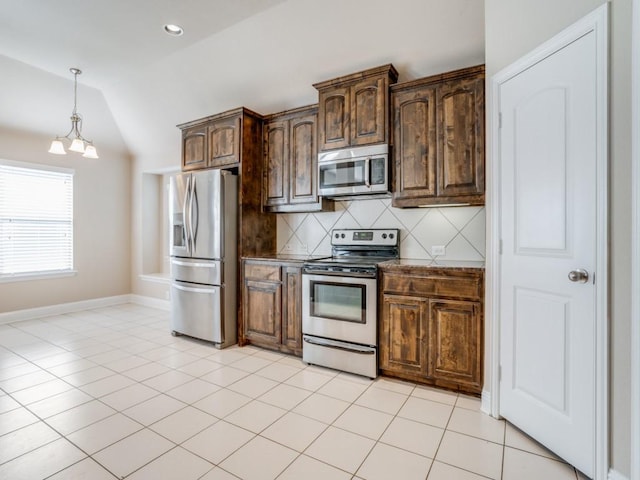 kitchen with light tile patterned floors, lofted ceiling, stainless steel appliances, decorative light fixtures, and backsplash