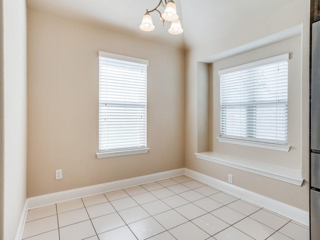 empty room with a notable chandelier, plenty of natural light, and baseboards