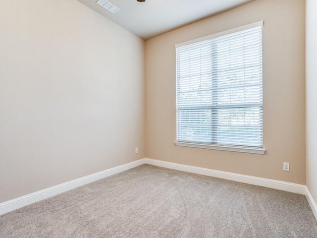 spare room with carpet, visible vents, and baseboards