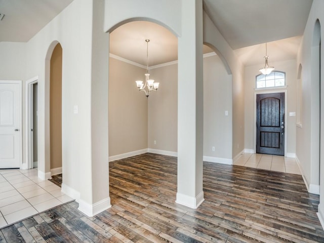 foyer entrance featuring crown molding, wood finished floors, baseboards, and a chandelier