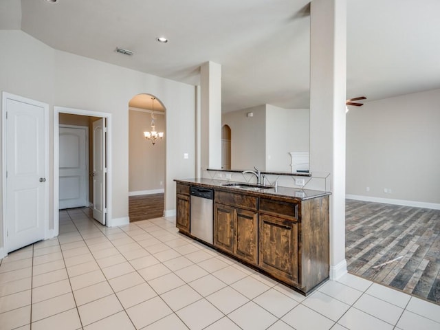 kitchen with light tile patterned floors, ceiling fan with notable chandelier, stainless steel dishwasher, arched walkways, and a sink