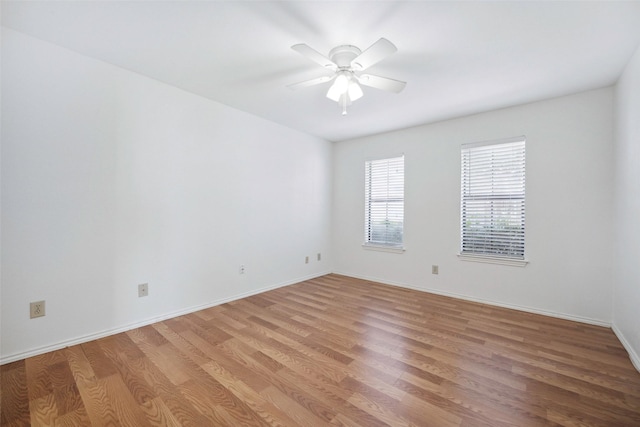 empty room featuring light wood-type flooring, baseboards, and a ceiling fan