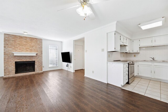 kitchen featuring light hardwood / wood-style flooring, a fireplace, ornamental molding, and stainless steel electric range oven