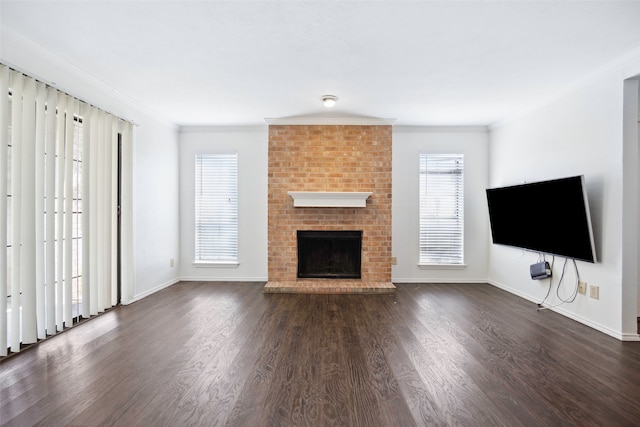 unfurnished living room featuring a fireplace, ornamental molding, dark hardwood / wood-style floors, and a healthy amount of sunlight