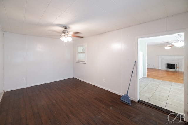 spare room with ceiling fan, hardwood / wood-style flooring, and a brick fireplace