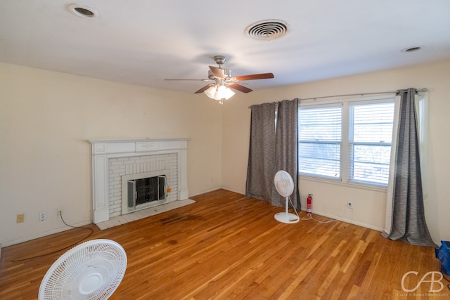 living room featuring ceiling fan, light hardwood / wood-style flooring, and a fireplace