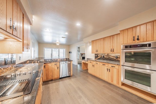 kitchen with tasteful backsplash, light brown cabinetry, appliances with stainless steel finishes, kitchen peninsula, and light hardwood / wood-style flooring