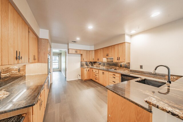 kitchen with sink, light hardwood / wood-style floors, dark stone counters, decorative backsplash, and light brown cabinets