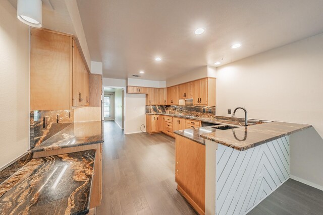 kitchen with light brown cabinetry, sink, kitchen peninsula, hardwood / wood-style flooring, and decorative backsplash