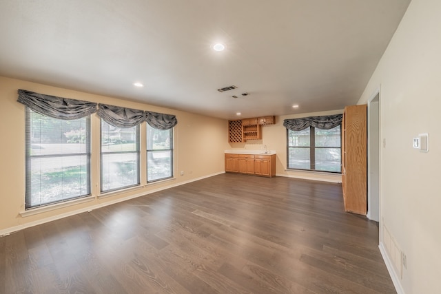 unfurnished living room featuring sink, a wealth of natural light, and dark hardwood / wood-style floors