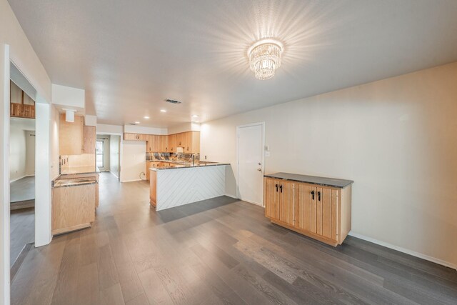 kitchen with light brown cabinets, kitchen peninsula, dark hardwood / wood-style floors, and an inviting chandelier