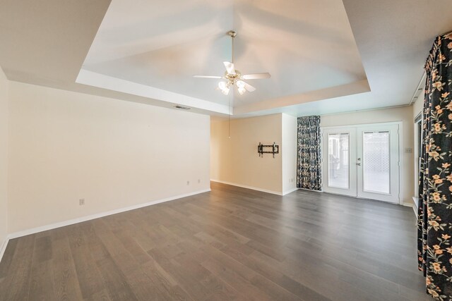 spare room with french doors, ceiling fan, a raised ceiling, and dark hardwood / wood-style floors