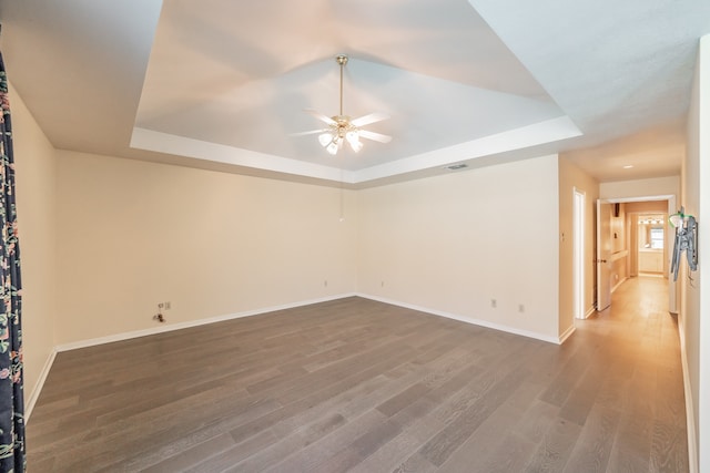 unfurnished room featuring hardwood / wood-style flooring, a raised ceiling, and ceiling fan