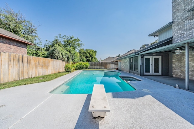 view of pool featuring a patio area, a fenced backyard, a diving board, and french doors