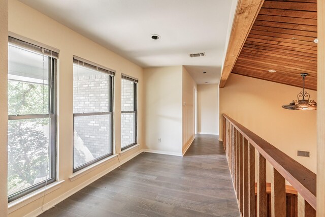 hall featuring beamed ceiling, dark wood-type flooring, and plenty of natural light