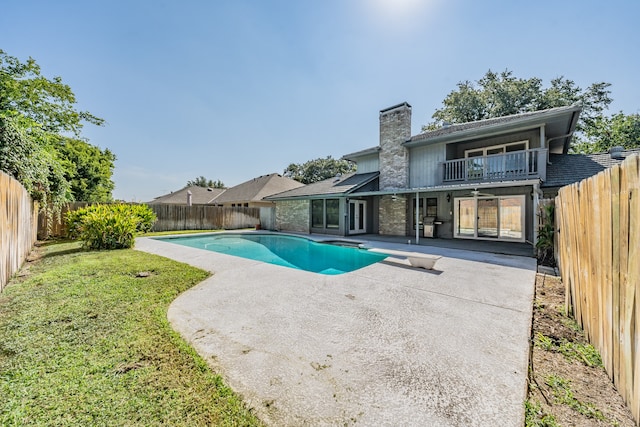 view of swimming pool featuring a yard, a patio area, and a diving board