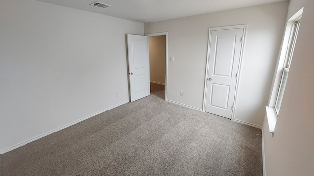 unfurnished bedroom with multiple windows, light colored carpet, and a closet