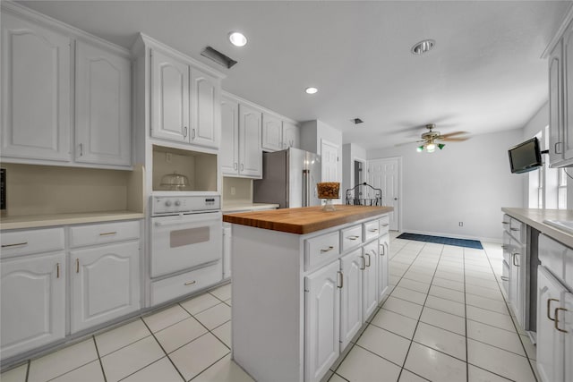 kitchen featuring a kitchen island, oven, butcher block countertops, high end refrigerator, and white cabinetry