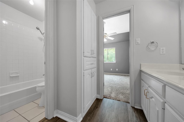 full bathroom with a ceiling fan, baseboards, toilet, vanity, and  shower combination