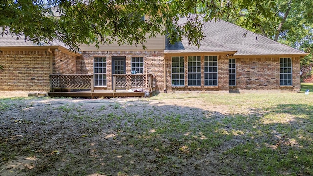 back of property with brick siding, a lawn, a wooden deck, and roof with shingles