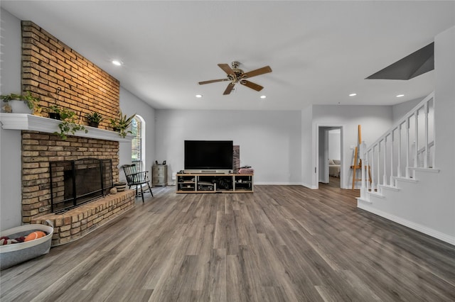 unfurnished living room featuring wood finished floors, recessed lighting, stairway, a fireplace, and baseboards