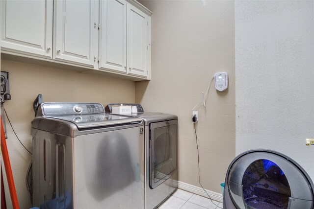 washroom featuring washer and clothes dryer, light tile patterned floors, and cabinets