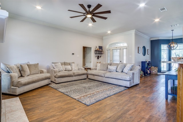 living room with ceiling fan with notable chandelier, dark hardwood / wood-style floors, and crown molding