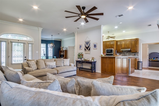 living room featuring ceiling fan, ornamental molding, and light hardwood / wood-style flooring