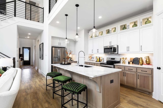 kitchen with appliances with stainless steel finishes, dark wood-style flooring, a sink, and an island with sink