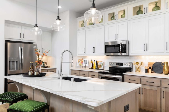 kitchen with decorative backsplash, decorative light fixtures, stainless steel appliances, a kitchen bar, and a sink