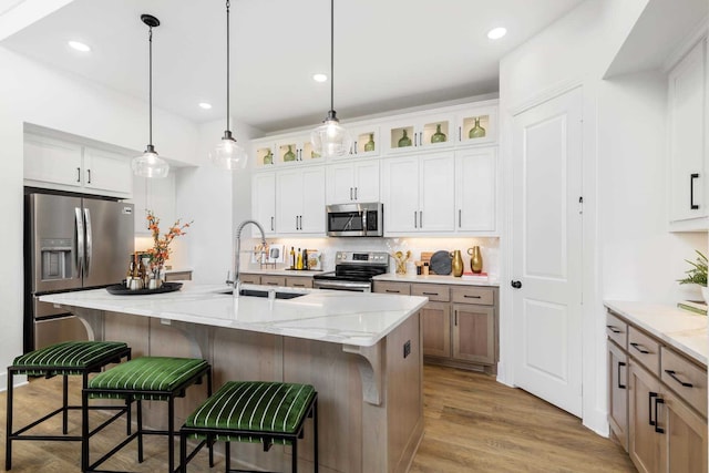 kitchen with stainless steel appliances, tasteful backsplash, glass insert cabinets, a sink, and wood finished floors