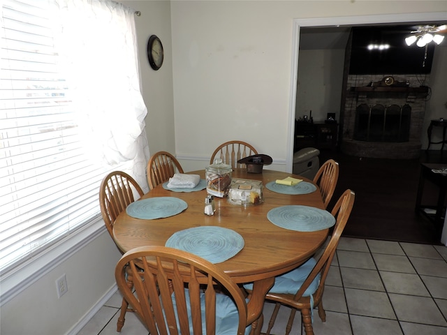 tiled dining area featuring a fireplace and ceiling fan